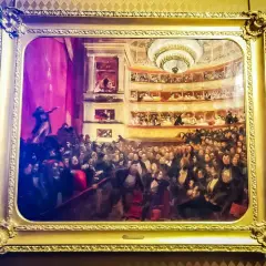 Obraz przedstawia tłum w teatrze, być może inspirowany **najważniejszymi dziełami Victora Hugo**, z widownią i lożami.