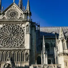 Katedra Notre-Dame z rozetą i wieżyczkami na tle błękitnego nieba.