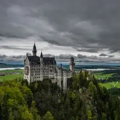 Bajkowy zamek Disneya w Niemczech, Neuschwanstein, wznosi się na skalistym wzgórzu, otoczony zielonymi lasami i malowniczym jeziorem.