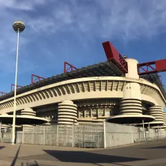 Stadion San Siro z czerwonymi elementami dachu i charakterystycznymi wieżami. Marzenie o meczu i zakup san siro bilety.