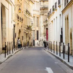 Urokliwa uliczka w paryskiej dzielnicy Le Marais, z kamiennymi budynkami i latarniami.