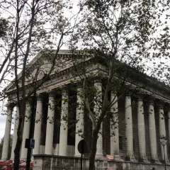 Kościół Madeleine w Paryżu z kolumnadą i drzewami na pierwszym planie.