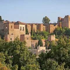 Malaga zamek, starożytna forteca z cegły i kamienia, wznosi się na wzgórzu pośród zieleni.