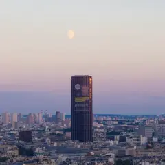 Wieżowiec Montparnasse w Paryżu z księżycem na niebie o zachodzie słońca.