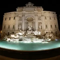 Fontanna di Trevi nocą, w blasku świateł, z turkusową wodą i rzeźbami.