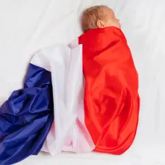 Noworodek owinięty w flagę Francji na białym tle.