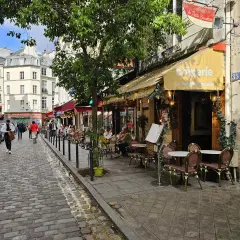 Ulica w dzielnicy łacińskiej Paryża z kawiarnią "La Petite Boulangerie" i brukowanym chodnikiem.