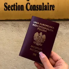Polski paszport w dłoni przed tabliczką "Section Consulaire". Czy do Francji trzeba paszport? Tak, jeśli nie jesteś obywatelem UE.