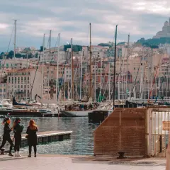 Widok na port w Marsylii z żaglówkami i budynkami w tle.