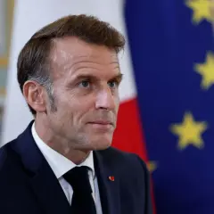 Emmanuel Macron na tle flagi Francji i UE. Czy we Francji jest ta sama godzina co w Polsce? Nie, jest godzina wcześniej.