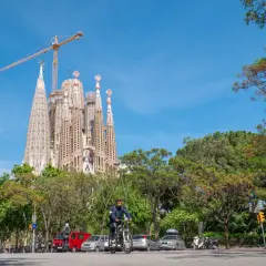 Rowerzysta mija Sagrada Familia, symbol Barcelony, podczas słonecznego dnia. Zwiedzanie tej niezwykłej budowli to marzenie wielu.