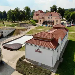 Widok z lotu ptaka na Hotel Da Vinci z czerwonym dachem, otoczony zielenią i innymi budynkami.