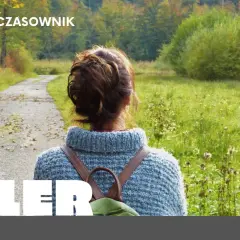 Kobieta w swetrze i plecaku idzie ścieżką przez jesienny las.
