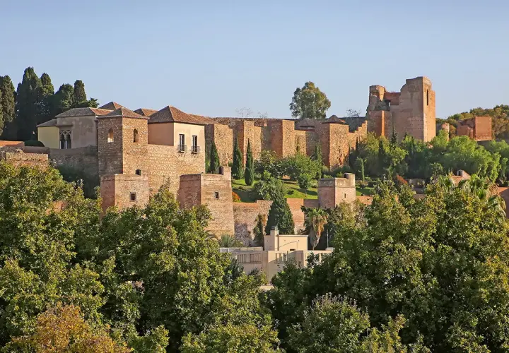 Malaga zamek, starożytna forteca z cegły i kamienia, wznosi się na wzgórzu pośród zieleni.