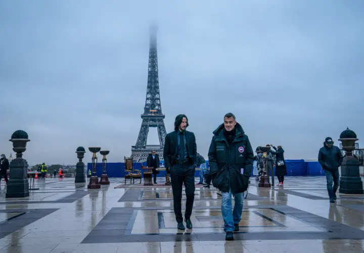 Dwóch mężczyzn idzie po placu przed wieżą Eiffla w Paryżu.