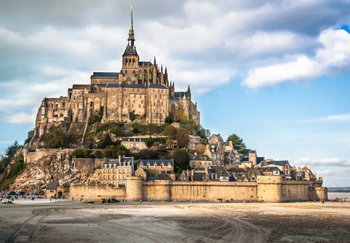 Mont-Saint-Michel, średniowieczny zamek na wyspie we Francji, z widokiem na piaszczyste wybrzeże.