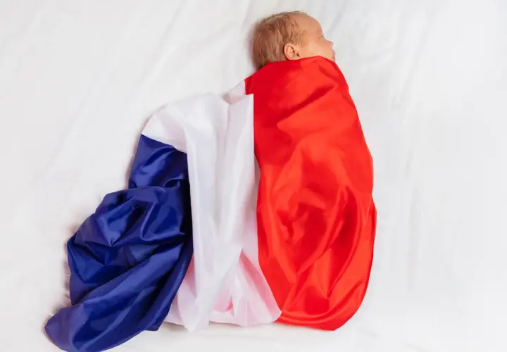 Noworodek owinięty w flagę Francji na białym tle.