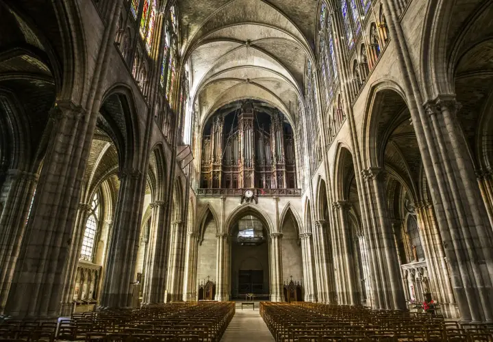 Wnętrze katedry Saint-Denis z organami i witrażami. Puste ławki czekają na wiernych w tej zabytkowej budowli.