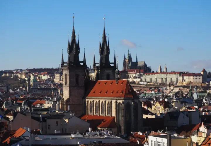 Gotycka wieża w Pradze góruje nad miastem, a w tle widać zamek.