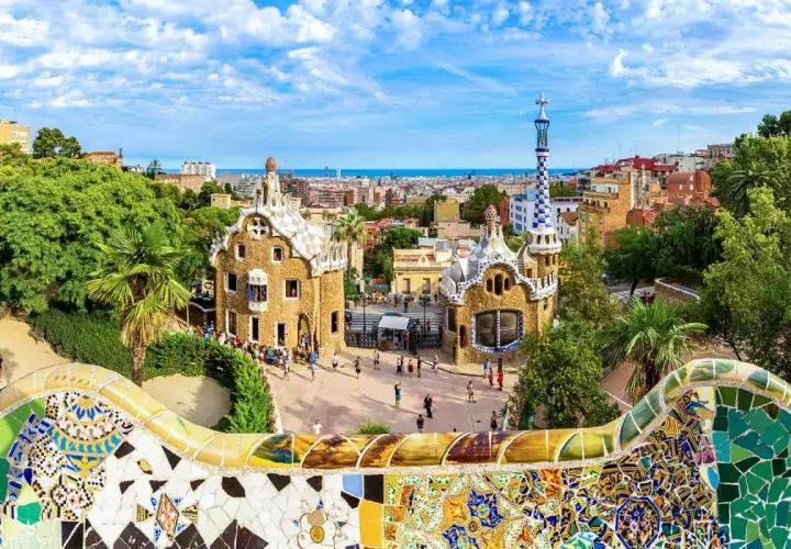 Kolorowa mozaika wita podczas zwiedzania Parku Güell. W tle bajkowe domki i panorama Barcelony.