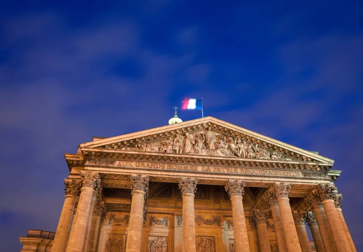 Panteon w Paryżu, symbol tego, z czego słynie Francja: wielkości i sztuki. Flaga Francji powiewa na tle nocnego nieba.