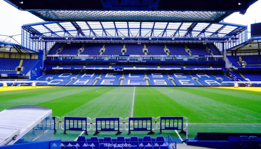 Puste trybuny stadionu Chelsea Londyn, zielona murawa i niebieskie siedzenia czekają na kibiców.