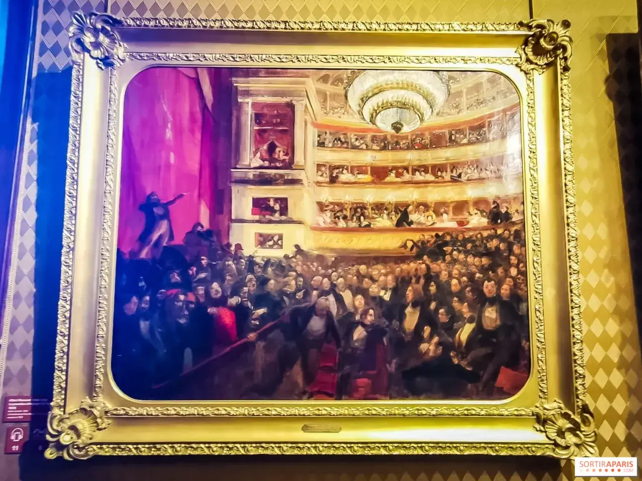 Obraz przedstawia tłum w teatrze, być może inspirowany **najważniejszymi dziełami Victora Hugo**, z widownią i lożami.