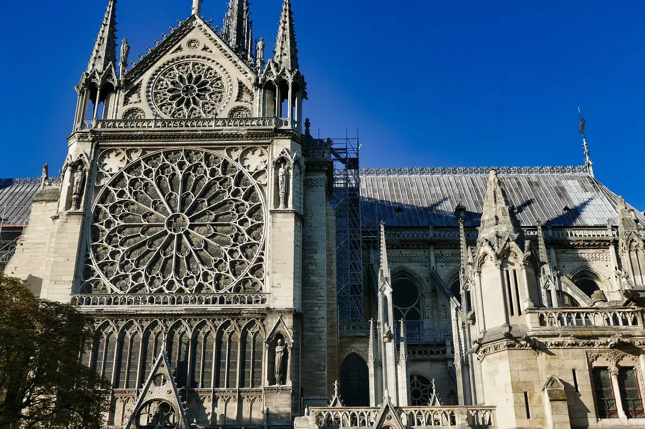 Katedra Notre-Dame z rozetą i wieżyczkami na tle błękitnego nieba.
