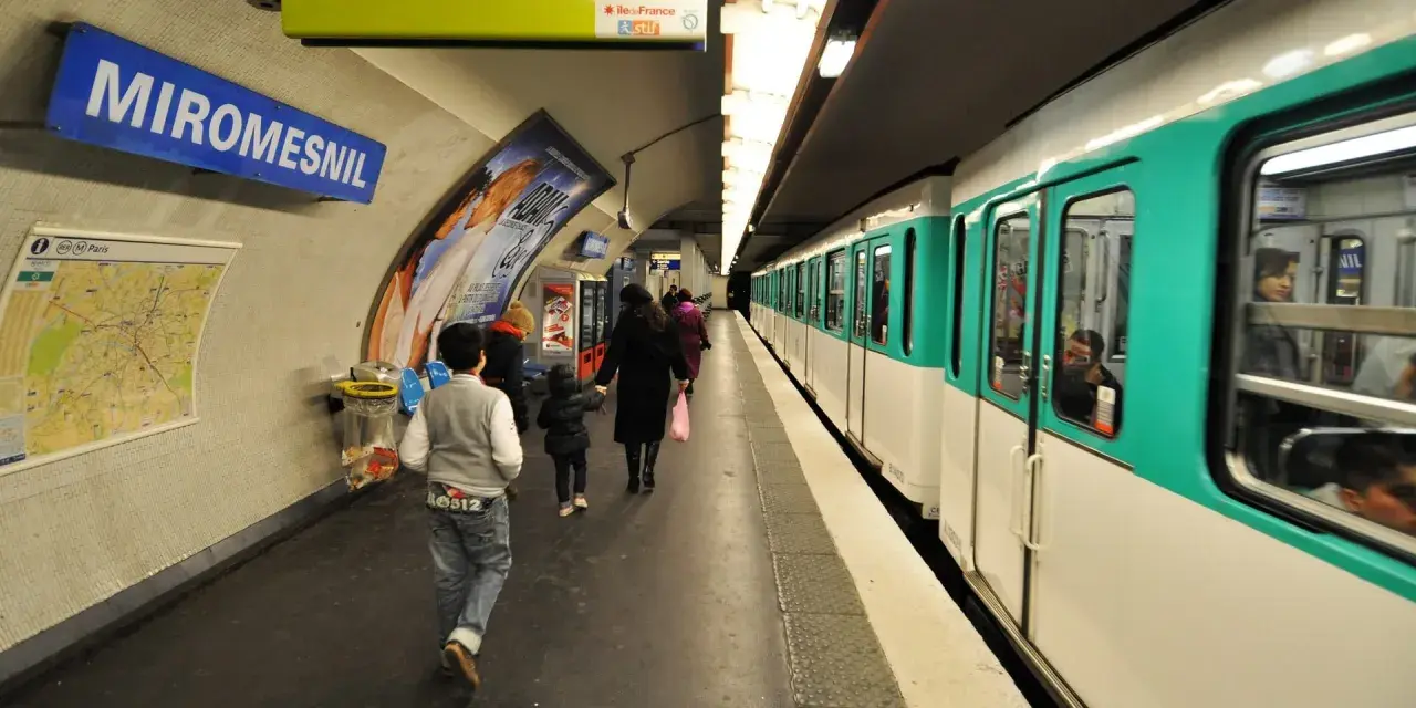 Na stacji Miromesnil w Paryżu widać pociąg metra. Ludzie czekają na peronie, a mapa metra wisi na ścianie.