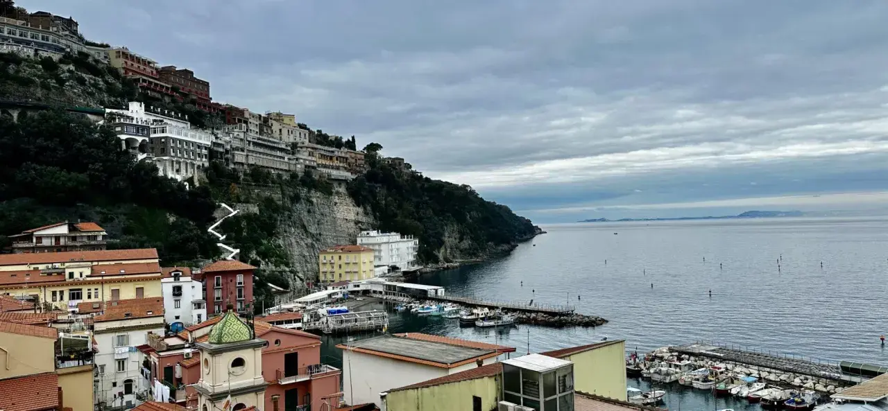 Widok na malownicze miasteczko na klifie i port w Sorrento. Warto zobaczyć te kolorowe domy i błękitne morze.