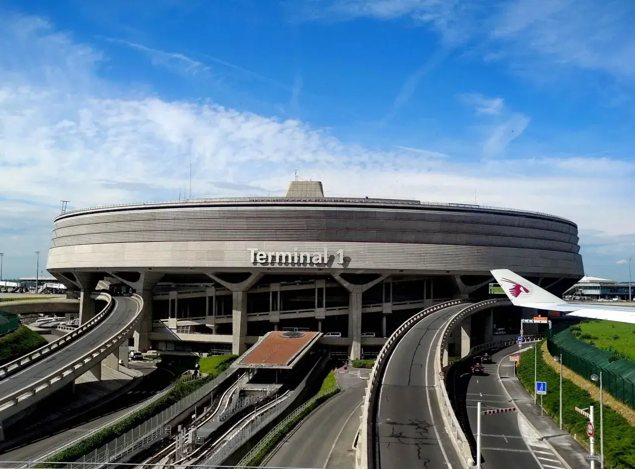 Terminal 1 lotniska Charles de Gaulle z drogami dojazdowymi i skrzydłem samolotu.