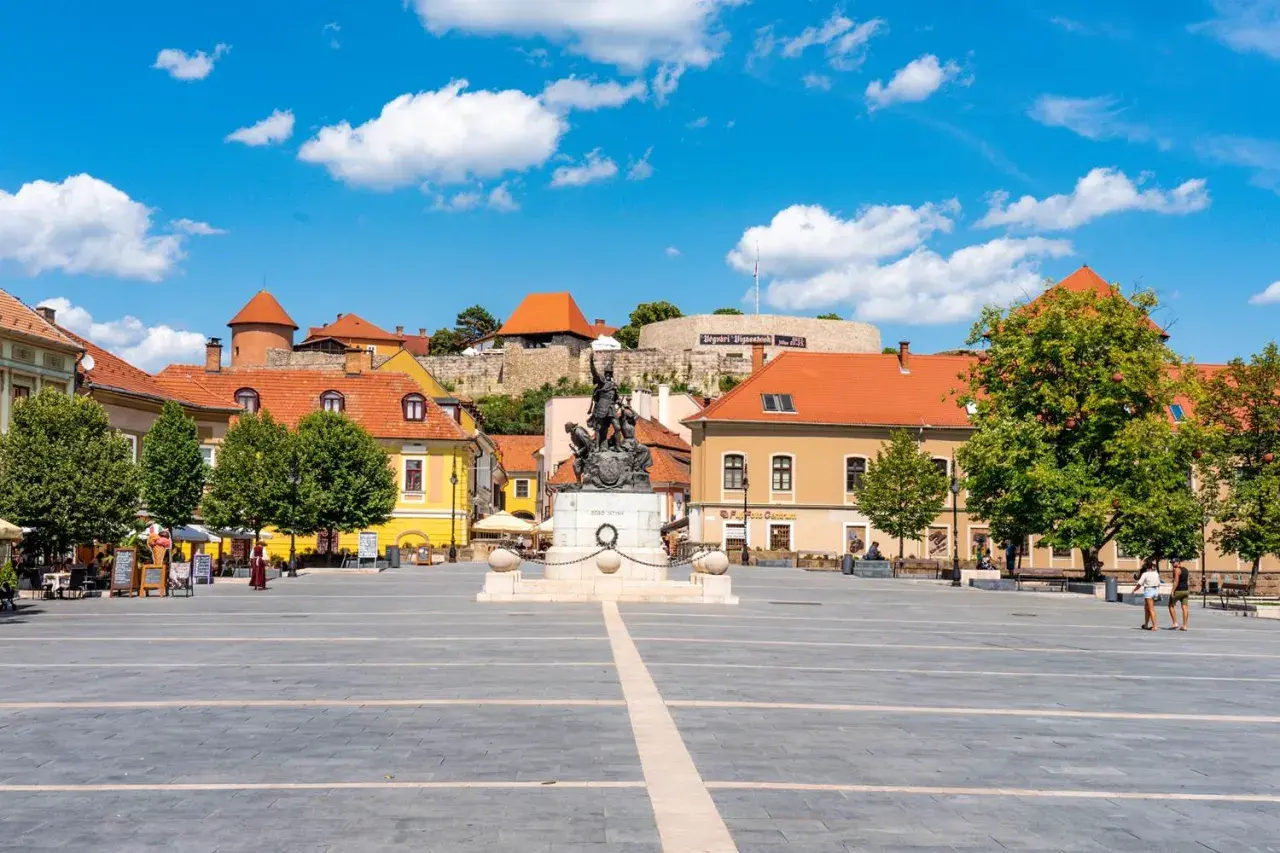 Rynek w Egerze z pomnikiem i zamkiem w tle. Odkryj atrakcje Egeru i okolic!