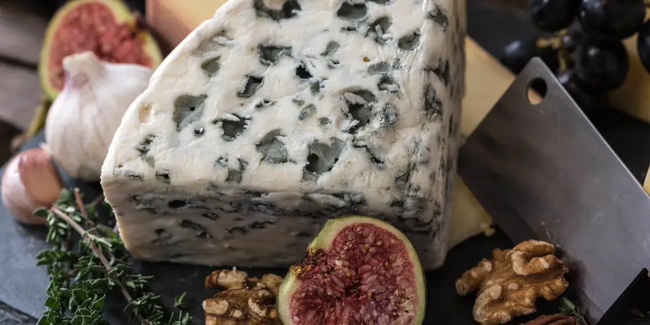 Kawałek sera pleśniowego z figą, orzechami i ziołami.