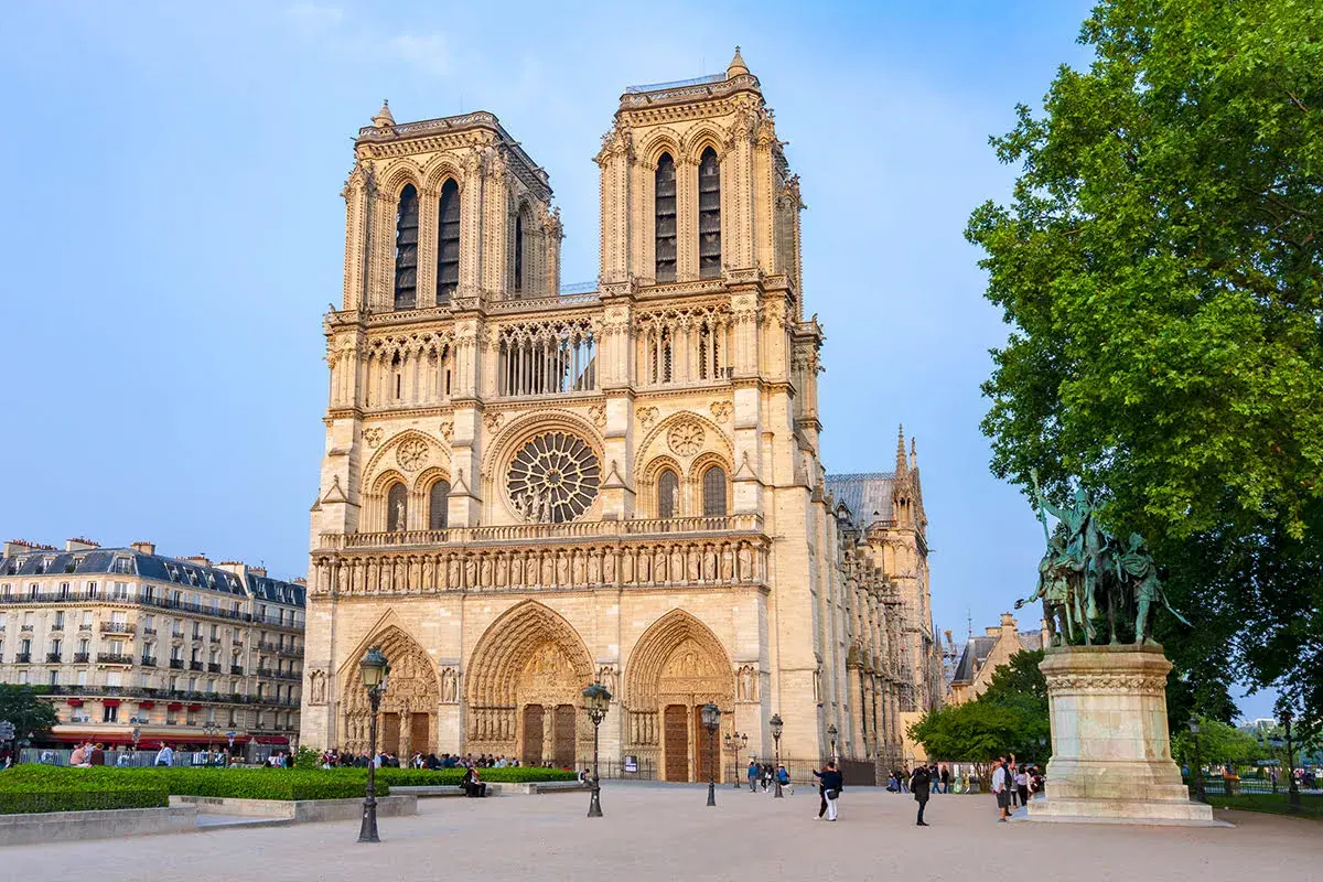 Katedra Notre Dame w Paryżu z placem i pomnikiem w słoneczny dzień.