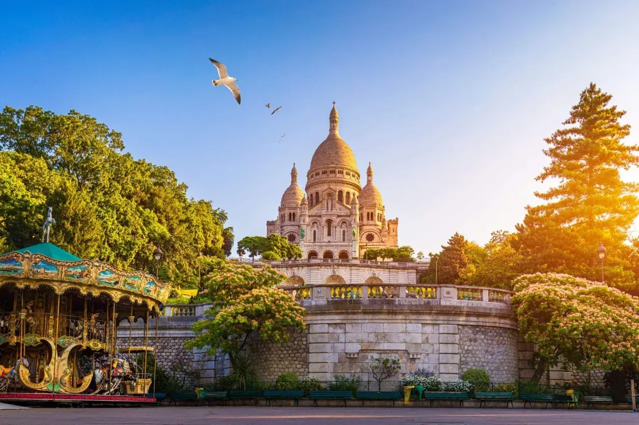 Bazylika Sacré-Cœur na Montmartre, Paryż, z karuzelą i mewą w locie.
