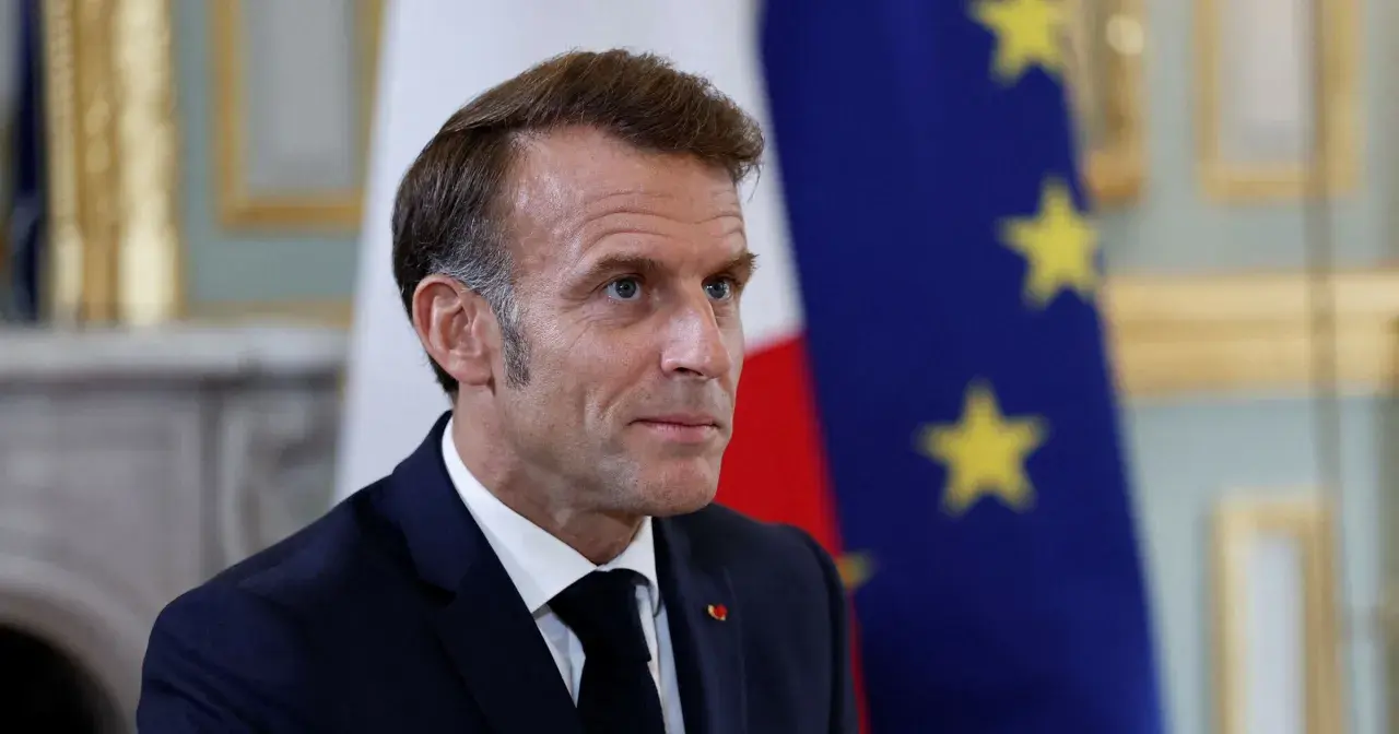 Emmanuel Macron na tle flagi Francji i UE. Czy we Francji jest ta sama godzina co w Polsce? Nie, jest godzina wcześniej.