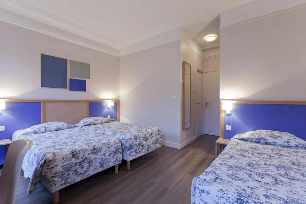 Pokój hotelowy z trzema łóżkami w niebiesko-białą pościelą i niebieskimi zagłówkami.