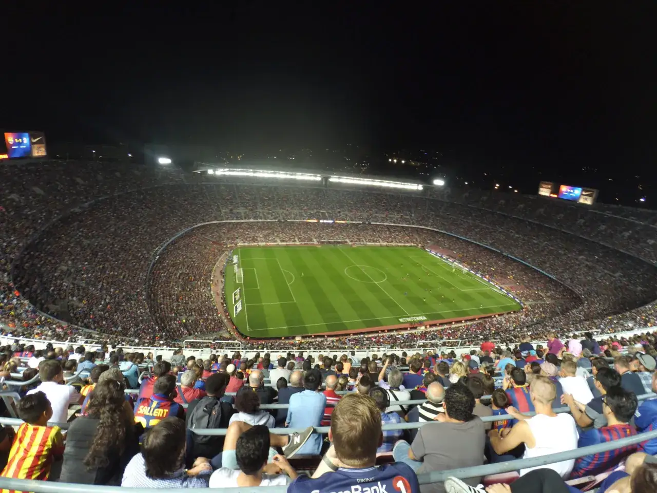 Nocne zwiedzanie Camp Nou. Tysiące kibiców na trybunach stadionu, zielona murawa i światła reflektorów tworzą niesamowitą atmosferę.