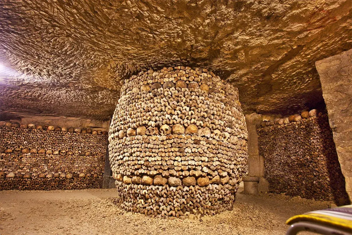 Wnętrze paryskich katakumb, gdzie ludzkie kości i czaszki tworzą imponujące, monumentalne formacje.