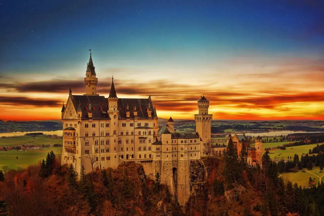 Bajkowy zamek z Disneya, Neuschwanstein, wznosi się na wzgórzu o zachodzie słońca.